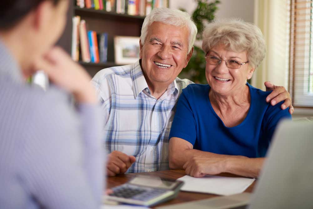 Matrimonio de edad mayor planeando su jubilación con asesor de Jinete y Asociados